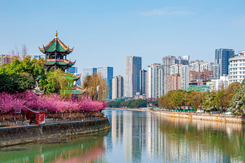 Padiglione Wangjiang durante la primavera con fiori di pesco a Chengdu, Sichuan, in Cina, affacciato sul fiume Jinjiang con edifici residenziali e per uffici sullo sfondo