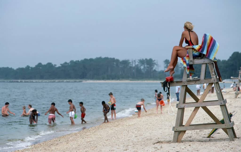 Bambini che giocano su una spiaggia con un bagnino che guarda