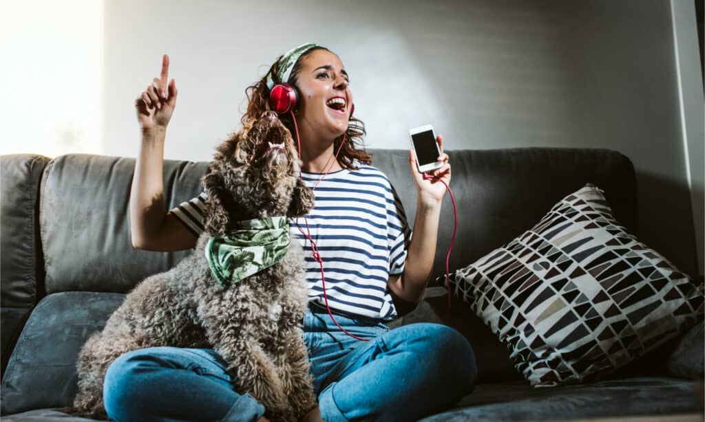 Una donna con le cuffie che canta con il suo cane