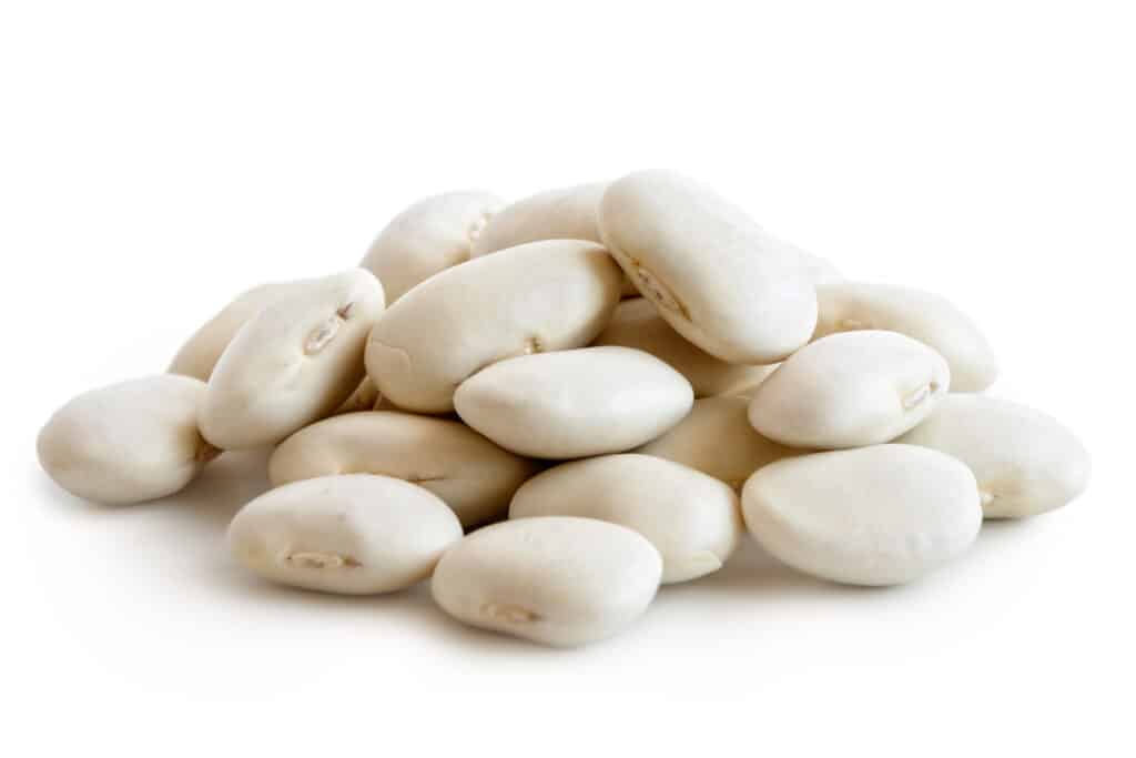 un mucchio di fagioli di lima biancastri secchi su uno sfondo bianco.