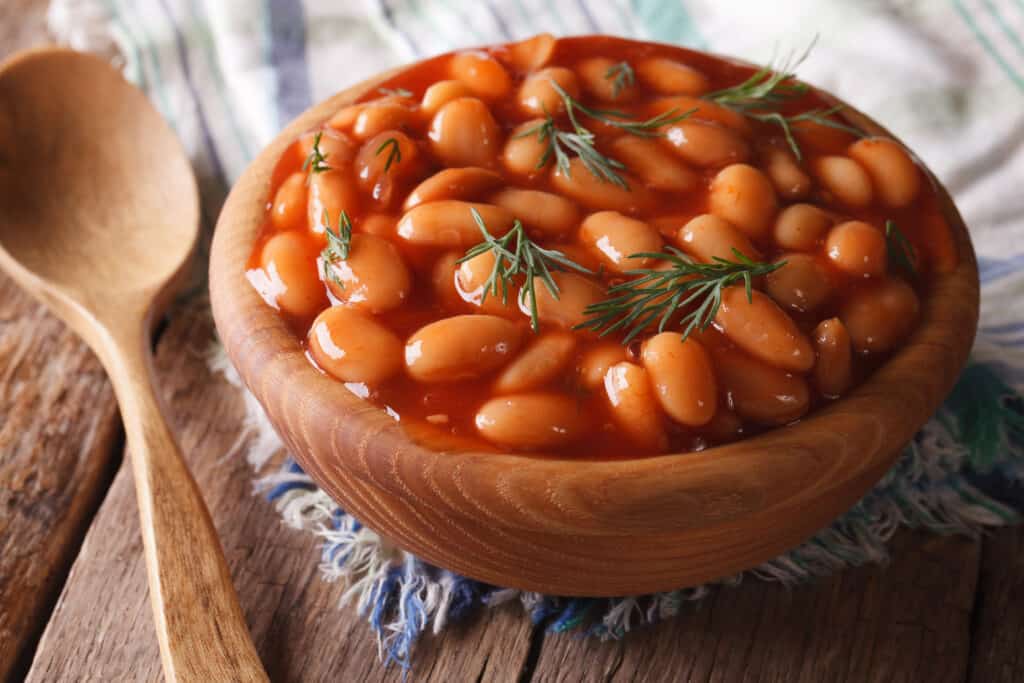 fagioli bianchi in salsa di pomodoro in una ciotola di legno alzato.  orizzontale
