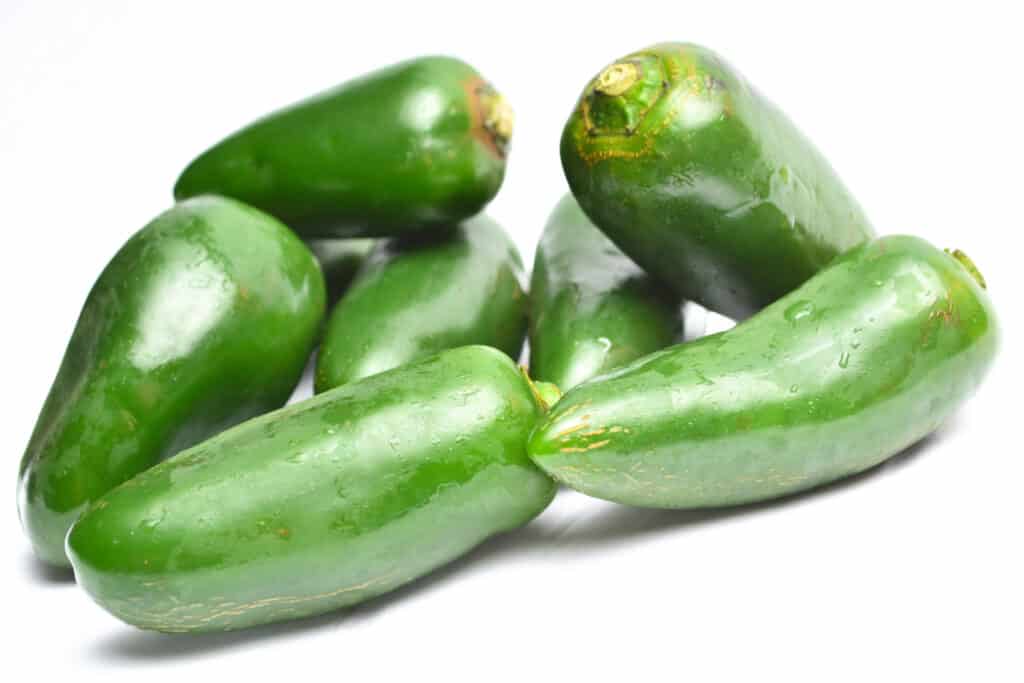 Un mucchio di peperoni Jalapeno isolati su sfondo bianco.
