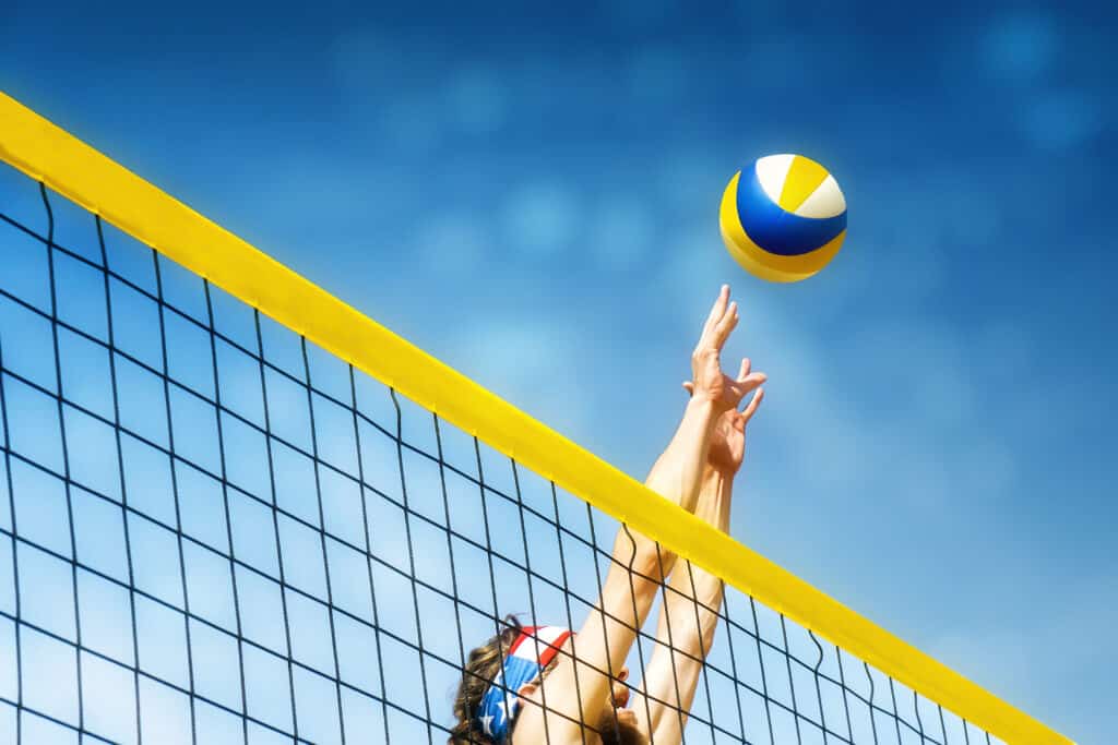 Le mani raggiungono una rete per colpire una pallavolo