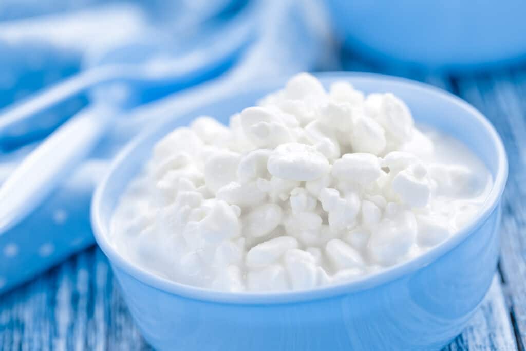 Una ciotola azzurra di ricotta su uno sfondo blu di un tovagliolo e tovaglietta
