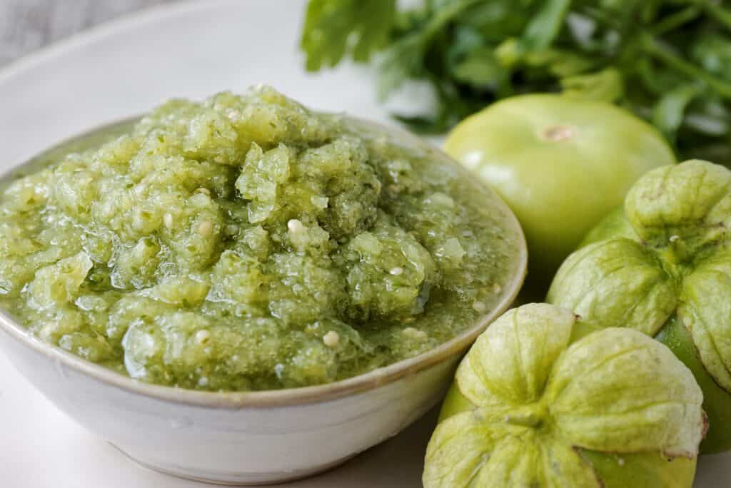 primo piano di salsa di tomatillo in una ciotola con tomatillos interi a lato