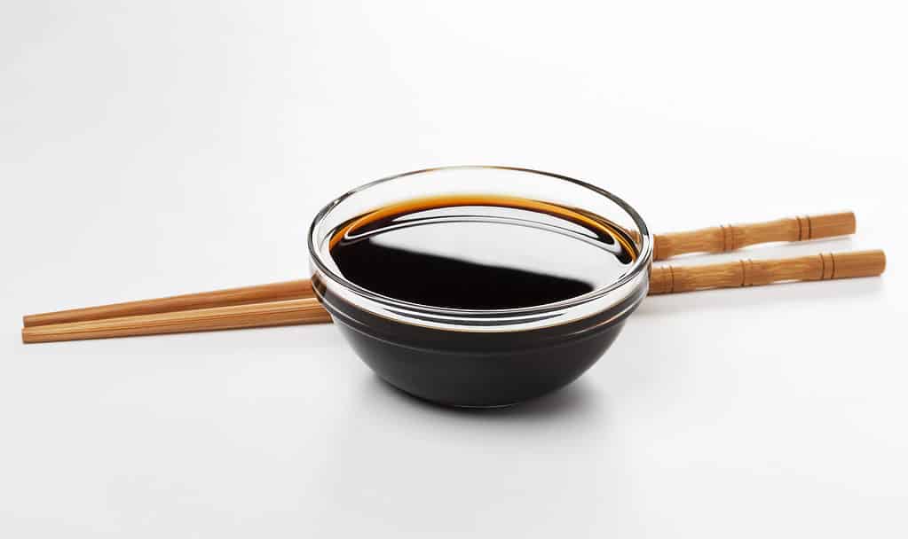 Salsa di soia e bacchette isolate su sfondo bianco