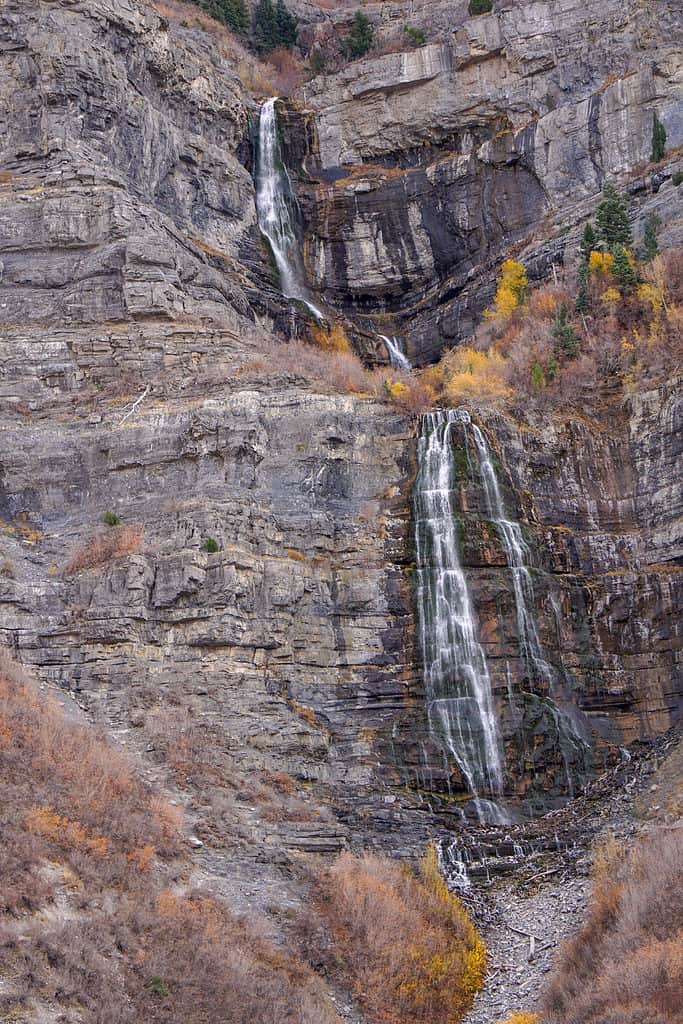 Vista di caduta di Bridal Veil Water Falls Utah Provo Canyon. La caduta è visibile verticalmente nella cornice centrale. Appare come due livelli separati. il livello superiore è singolare, mentre il livello inferiore è a doppia cascata. circondato da roccia e vegetazione secca, marrone-dorata