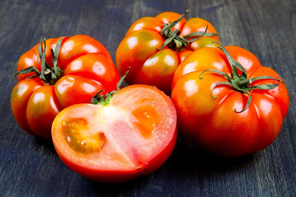 Pomodori interi e tagliati su una tavola di legno.