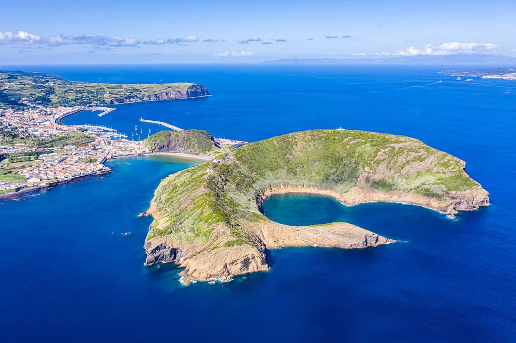 Parco naturale dei crateri vulcanici estinti distrutti di Caldeirinhas, montagna Guia, baia Baia do Porto Pim e porto, spiagge, porti turistici, tetti rossi della storica città di Horta, isola di Faial, Portogallo.