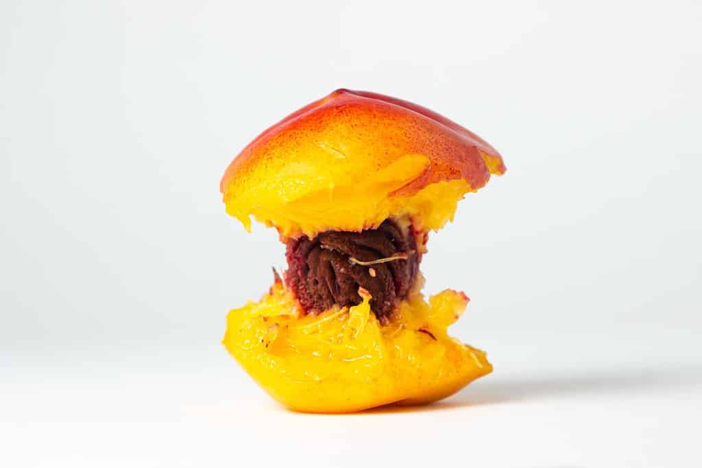 Pesca morsicata su sfondo bianco. Frutta deliziosa e succosa. nocciolo di pesca