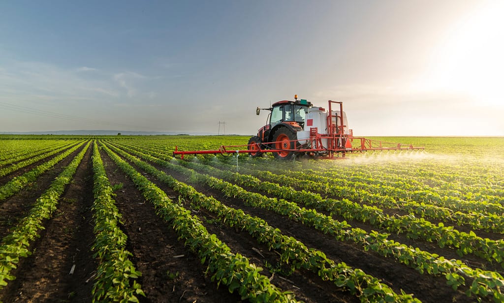 Trattore che spruzza pesticidi sul campo di soia con irroratrice in primavera
