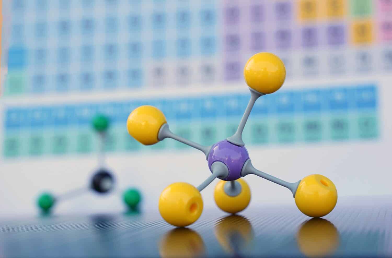 Simula la forma delle molecole covalenti su uno sfondo della tavola periodica.  Messa a fuoco morbida e selettiva.                                     