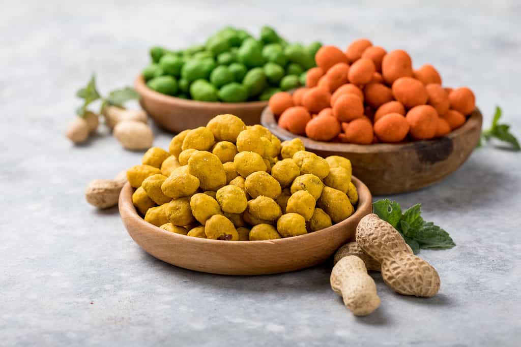 Assortimento di diversi snack di arachidi per birra, vino, party bar.  Arachidi salate, vasabi verde, peperoncino piccante rosso, glassa di formaggio giallo
