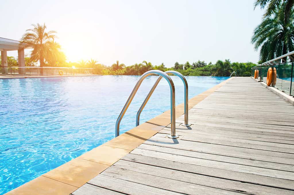 Piscina con scala e ponte di legno in hotel.