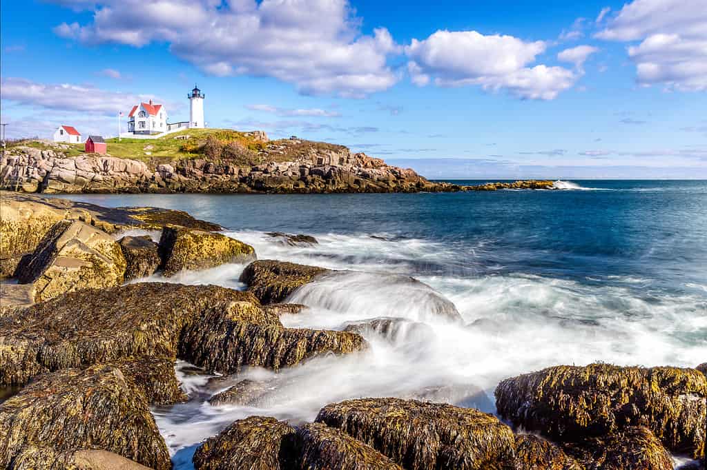Vista di una delle migliori spiagge del Maine con il faro di Cape Neddick sullo sfondo