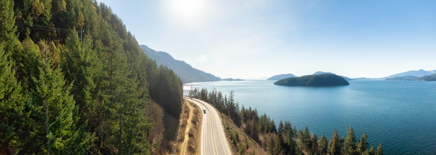 Vista panoramica aerea della Sea to Sky Highway sulla costa occidentale dell'Oceano Pacifico. Soleggiata giornata invernale. Situato a Howe Sound tra Vancouver e Squamish, British Columbia, Canada.