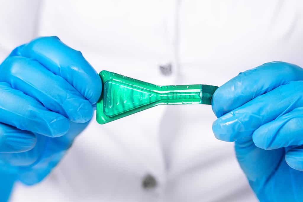 Medico in camice medico e guanti protettivi sterili in silicone bottiglia aperta di farmaco secondo la prescrizione con pipetta contro zecche, pulci e altri parassiti al garrese dei cani.