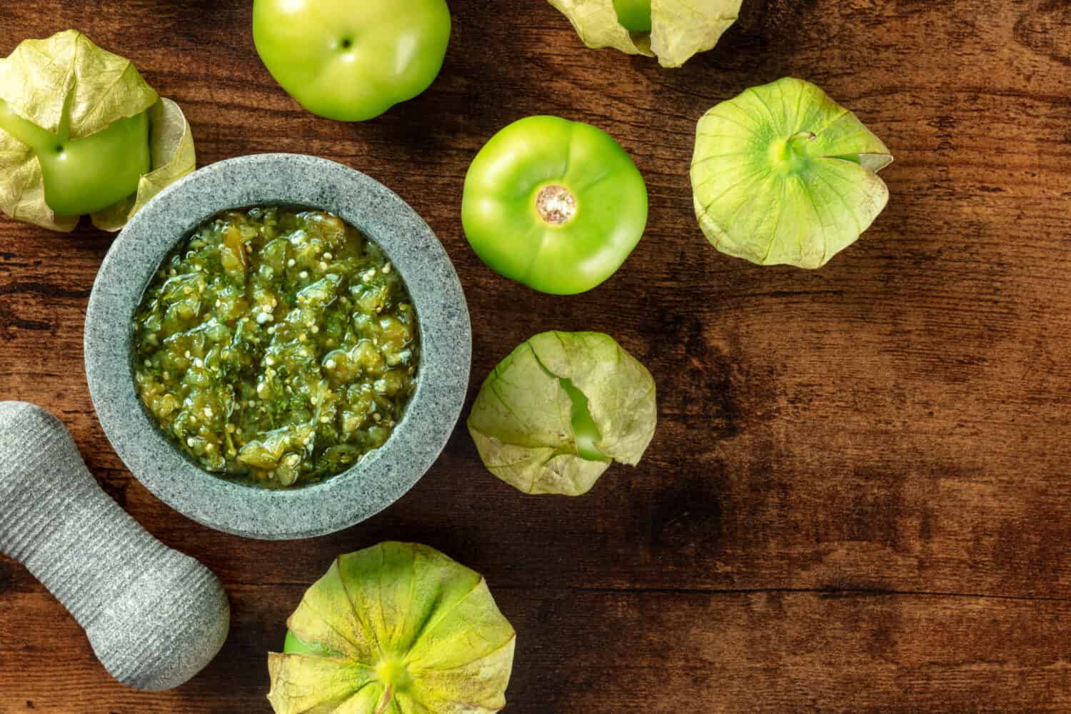 Tomatillos, pomodori verdi, con salsa verde, salsa verde, in un molcajete, mortaio messicano tradizionale, colpo piatto sopra la testa con un posto per il testo