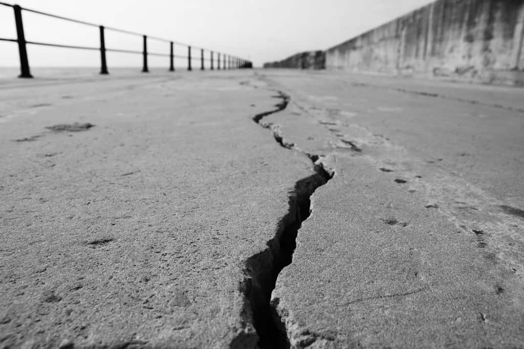 Una grande crepa nel cemento.  Foto di concetto di terremoto.  Questa immagine ha il fuoco selettivo.