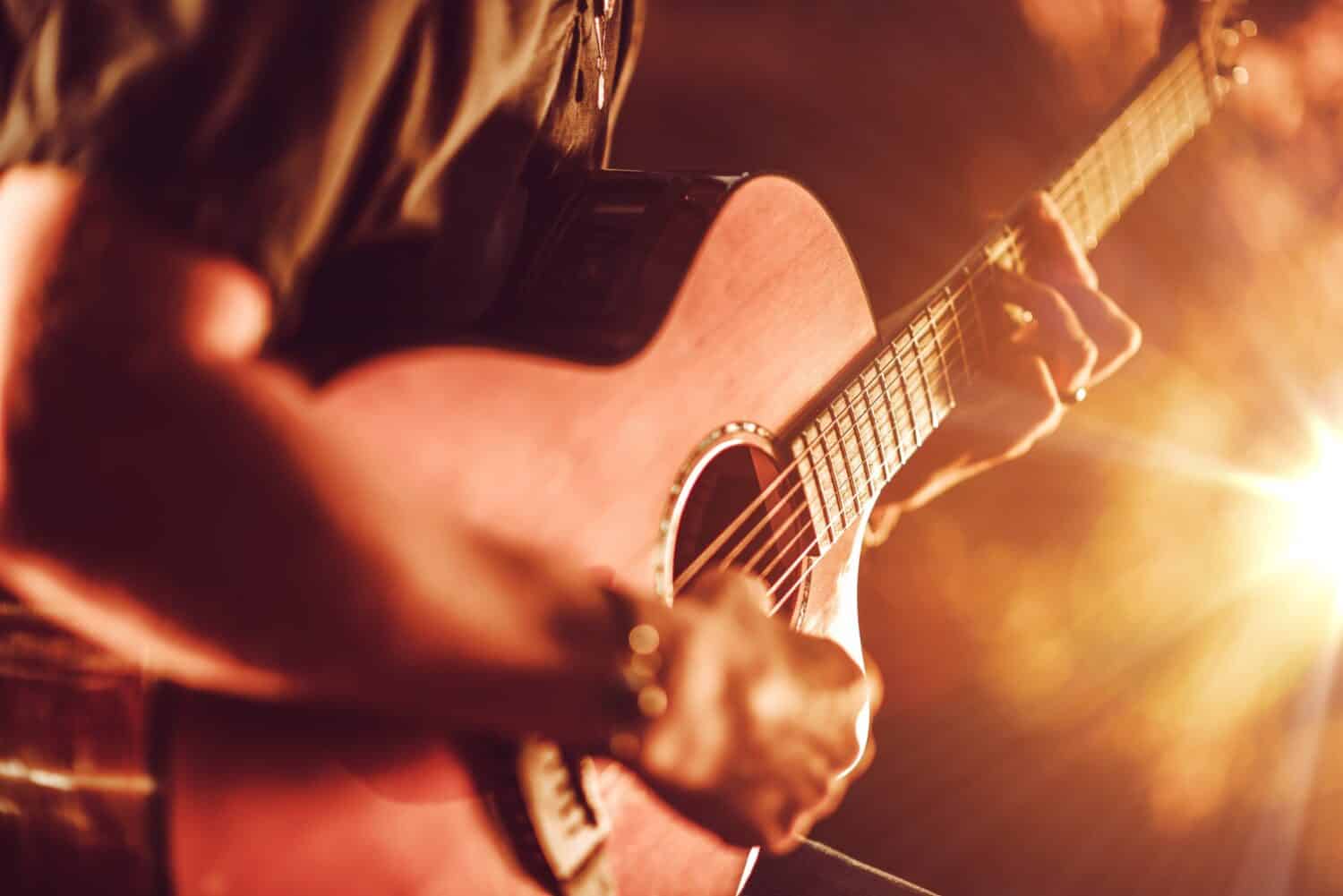 Suonare la chitarra acustica.  Uomini che giocano la fotografia del primo piano della chitarra acustica.