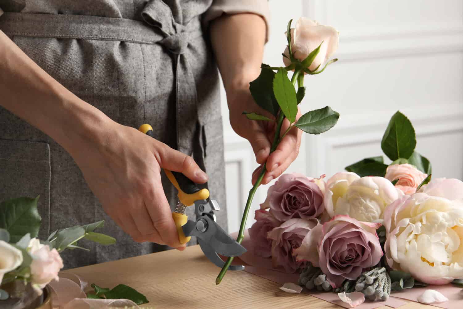 Fioraio taglio gambo di fiori con potatore sul posto di lavoro, primo piano