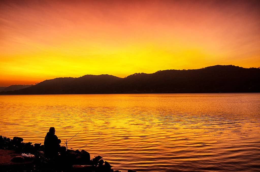 Un pescatore all'alba sulle rive di un fiume