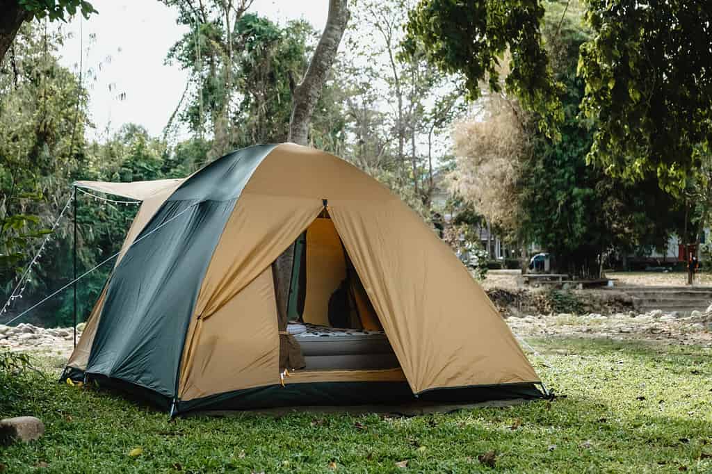 Campeggio picnic tenda verde campeggio nella foresta escursionistica all'aperto.  Camper durante il campeggio sullo sfondo della natura al campo estivo.  Concetto di vacanza viaggio avventura
