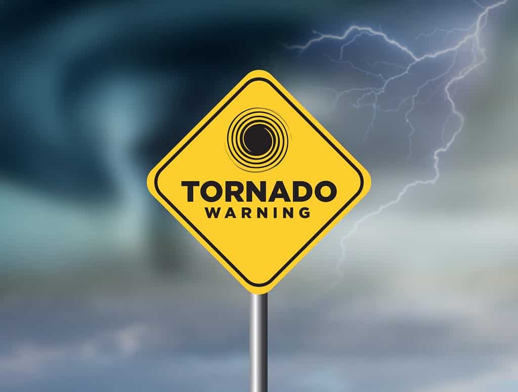 Segnale di avvertimento tornado contro un potente sfondo tempestoso con spazio per la copia. Il cartello sporco e angolato con venti ciclonici si aggiunge al dramma.