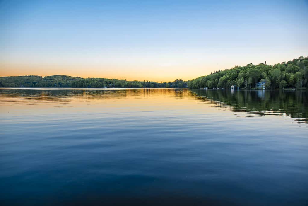 Un lago blu brillante circondato da alberi e colline.