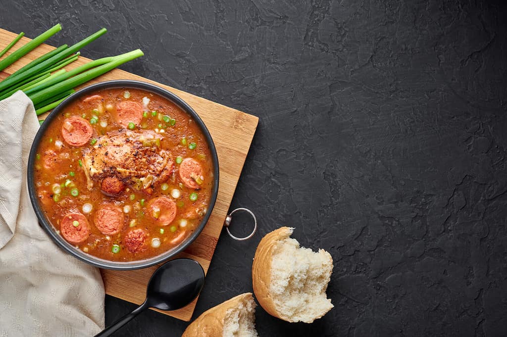 Zuppa di gumbo di pollo e salsiccia in ciotola nera su sfondo di ardesia scura. Il gumbo è una zuppa della cucina cajun della Louisiana con roux. Cibo americano USA. Pasto etnico tradizionale. Copia spazio