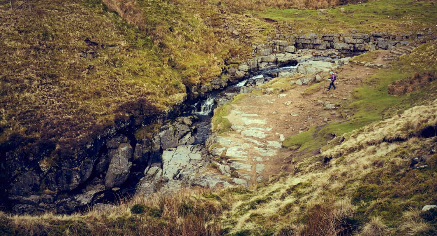 Un lontano escursionista all'ingresso di Gaping Gill Cave nella roccia calcarea delle Yorkshire Dales, Inghilterra.