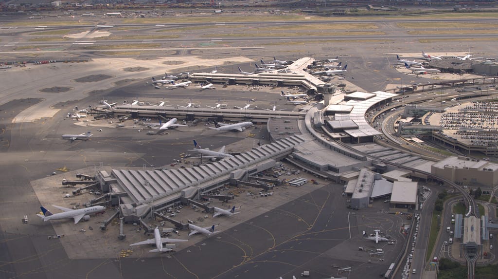 ANTENNA, PRIMO PIANO: Volare sopra gli aeroplani parcheggiati sul piazzale in attesa che i passeggeri salgano a bordo della jetway e inizino il loro viaggio di viaggio. Terminal dell'aeroporto internazionale di New York Newark