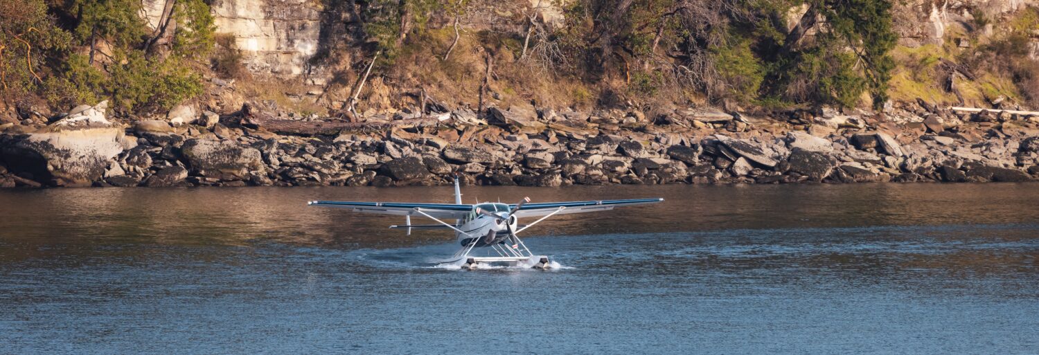Idrovolante in acqua pronto per il decollo con Rocky Shore in background.  Nanaimo, Isola di Vancouver, British Columbia, Canada.