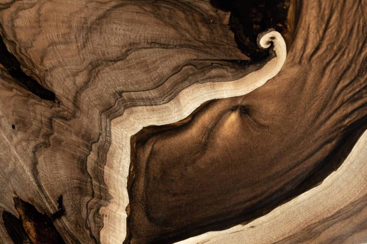 Mobili vintage costosi.  Il tavolo è rivestito con resina epossidica e verniciato.  Lavorazione del legno di qualità di lusso.  Tavolo in legno su uno sfondo scuro.  Un fiume epossidico dorato in una lastra di albero rettangolare.