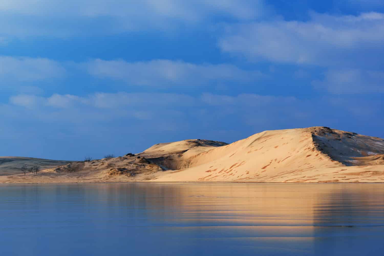 Il paesaggio invernale delle dune di sabbia del Silver Lake si riflette nel Silver Lake ghiacciato, Silver Lake state Park, Michigan, Stati Uniti