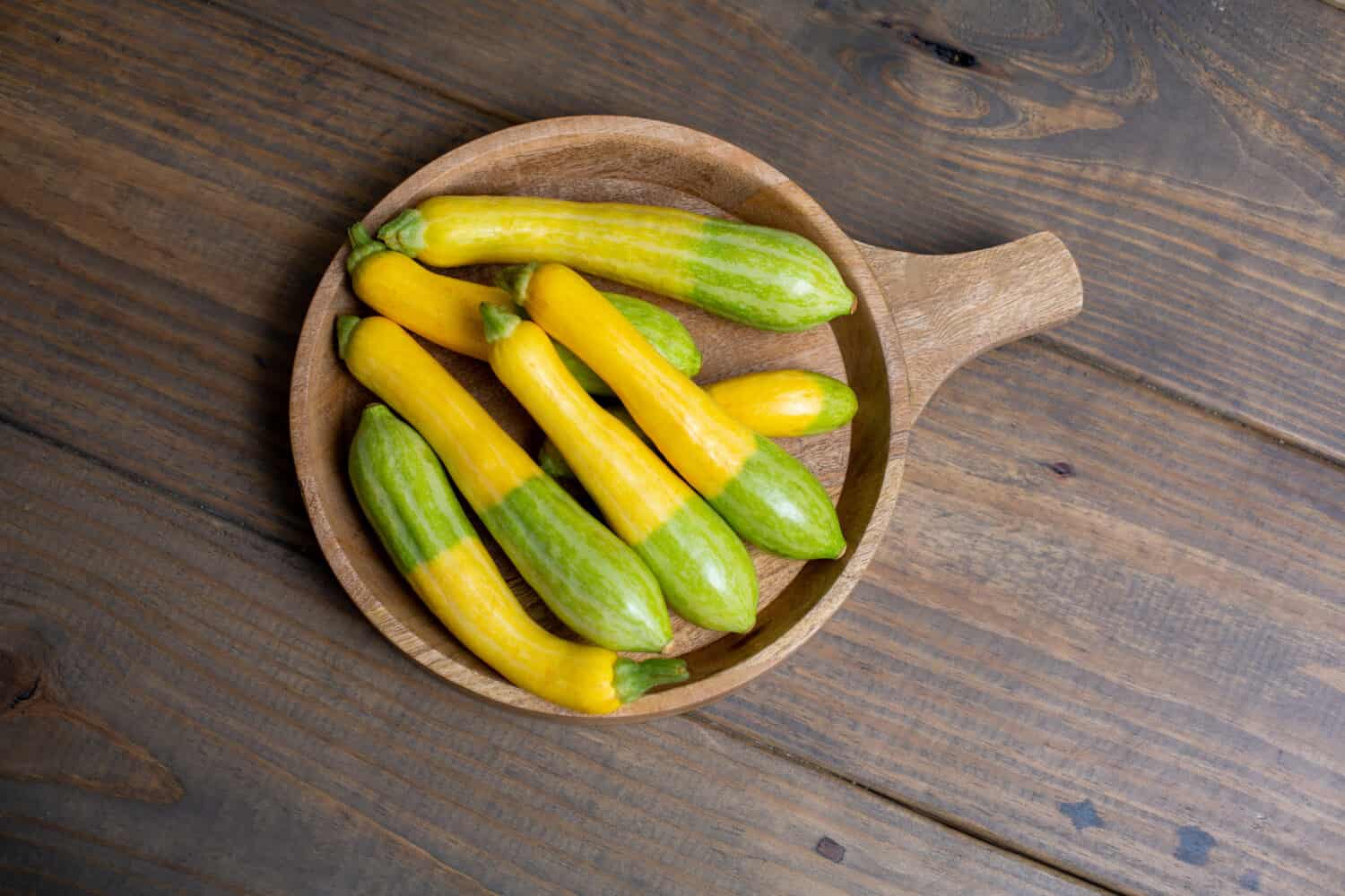 Vista dall'alto della zucca Zephyr fresca in una ciotola di legno su un tavolo di legno