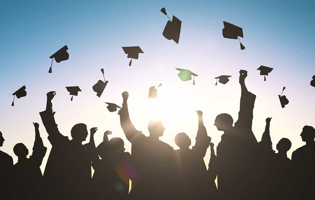 concetto di istruzione, laurea e persone - sagome di molti studenti felici in abiti che lanciano sparvieri in aria
