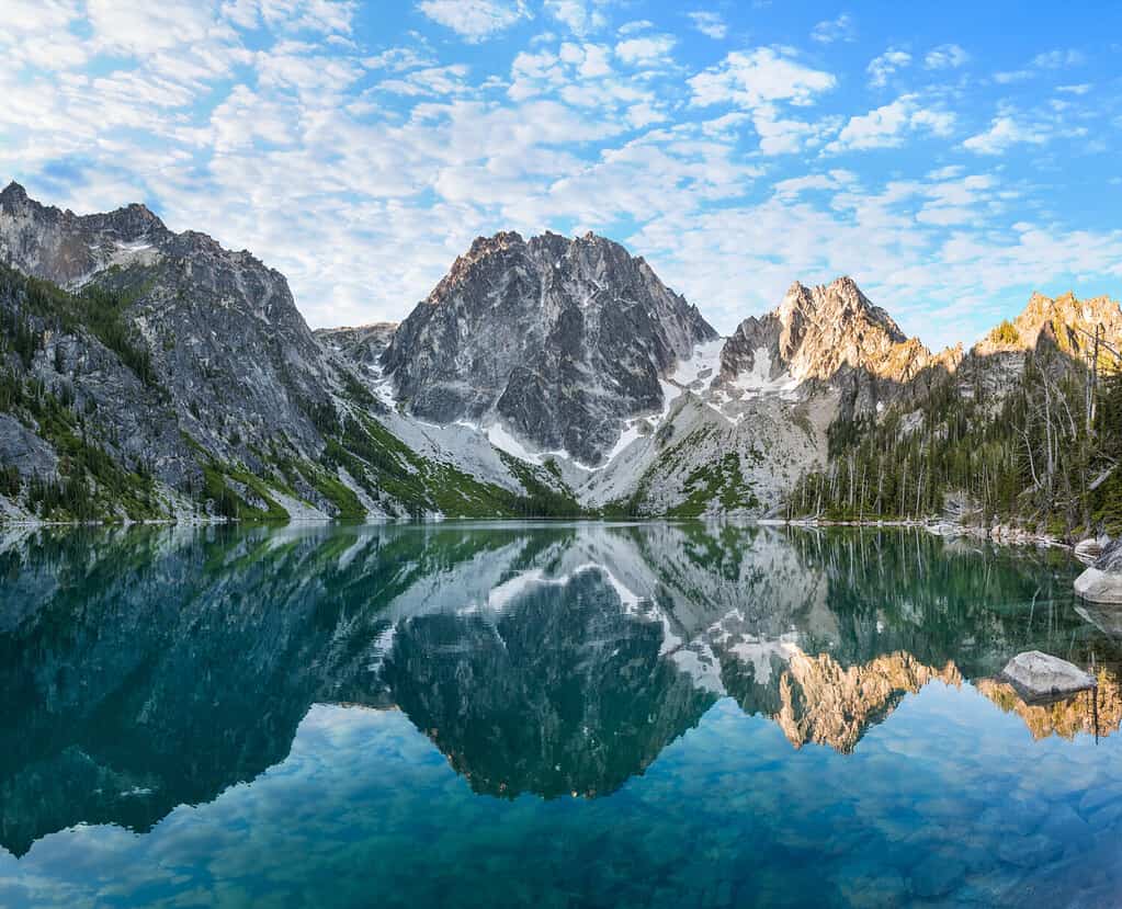 L'alba illumina Dragontail Peak, Colchuck Peak e Asgaard Pass sopra le acque Torquise del lago Colchuck.  Gli incantesimi, Cascade Mountains, Washington