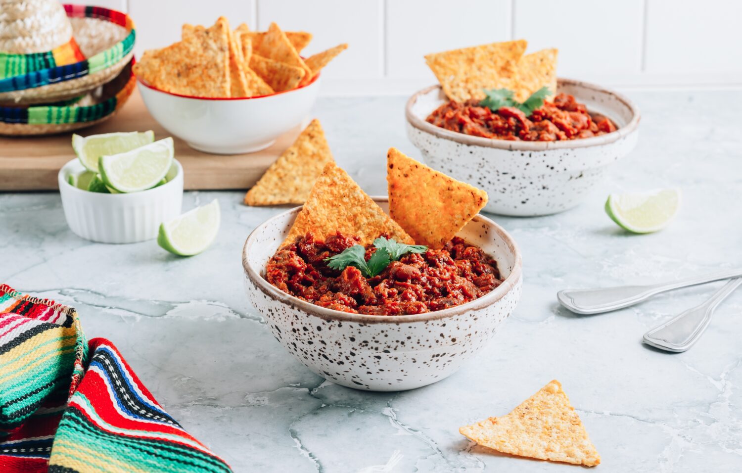 Chili con carne in ciotole con tortilla chips su sfondo di marmo grigio. Piatto tradizionale della cucina messicana. Messa a fuoco selettiva