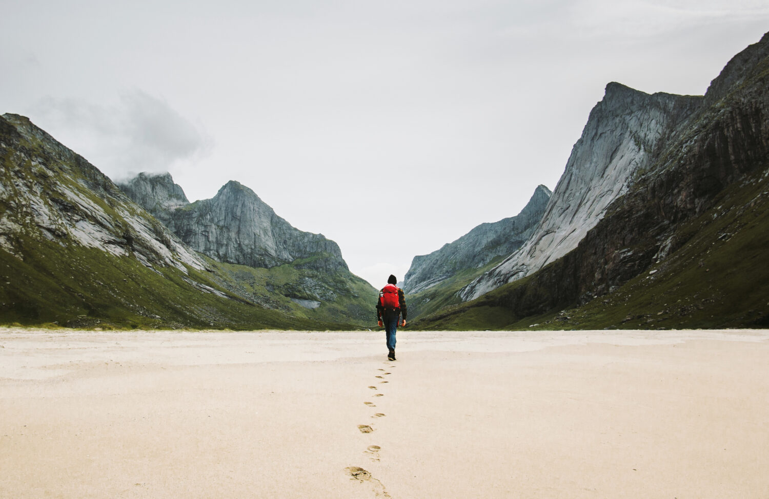 Uomo con zaino che cammina via da solo sulla spiaggia sabbiosa in montagna Viaggio stile di vita concetto avventura vacanze estive all'aperto nella natura selvaggia della Norvegia
