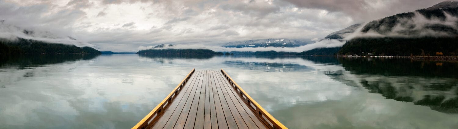Dock in legno sul lago Harrison, British Columbia, Canada. Sembra che un molo si stia dirigendo verso il nulla su un lago nel Pacifico nordoccidentale. Resort delle sorgenti termali di Harrison.