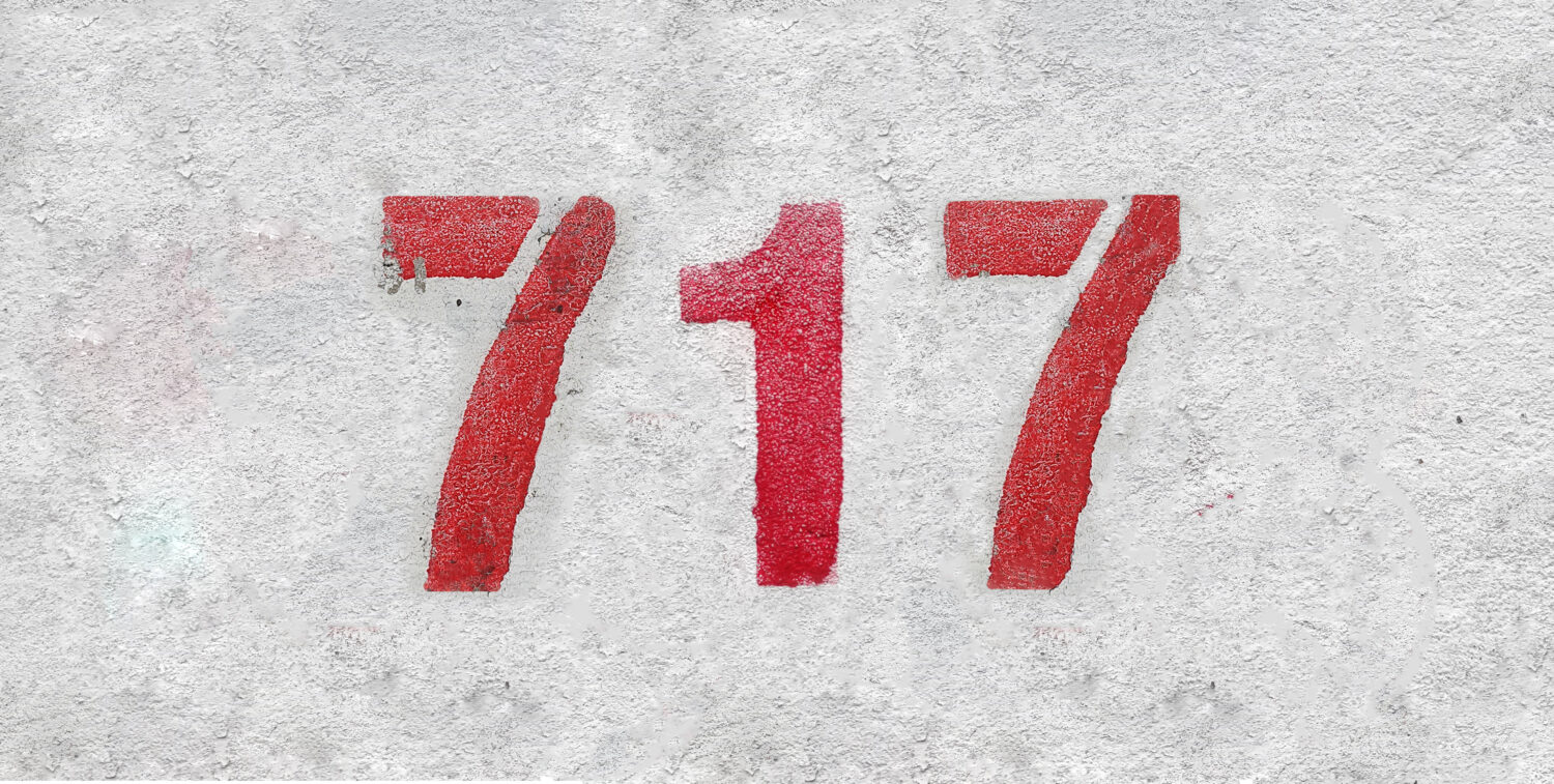 Numero rosso 717 sul muro bianco. Vernice spray.
