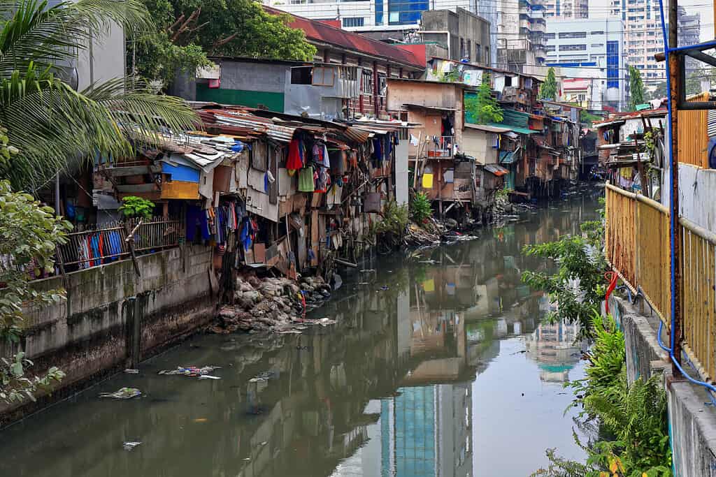 Vista verso N dal ponte di Soler Street alle rive affollate di baracche del canale Estero de San Lazaro del fiume Pasig-Torri Broadview sullo sfondo. Binondo Chinatown District-Manila-Filippine
