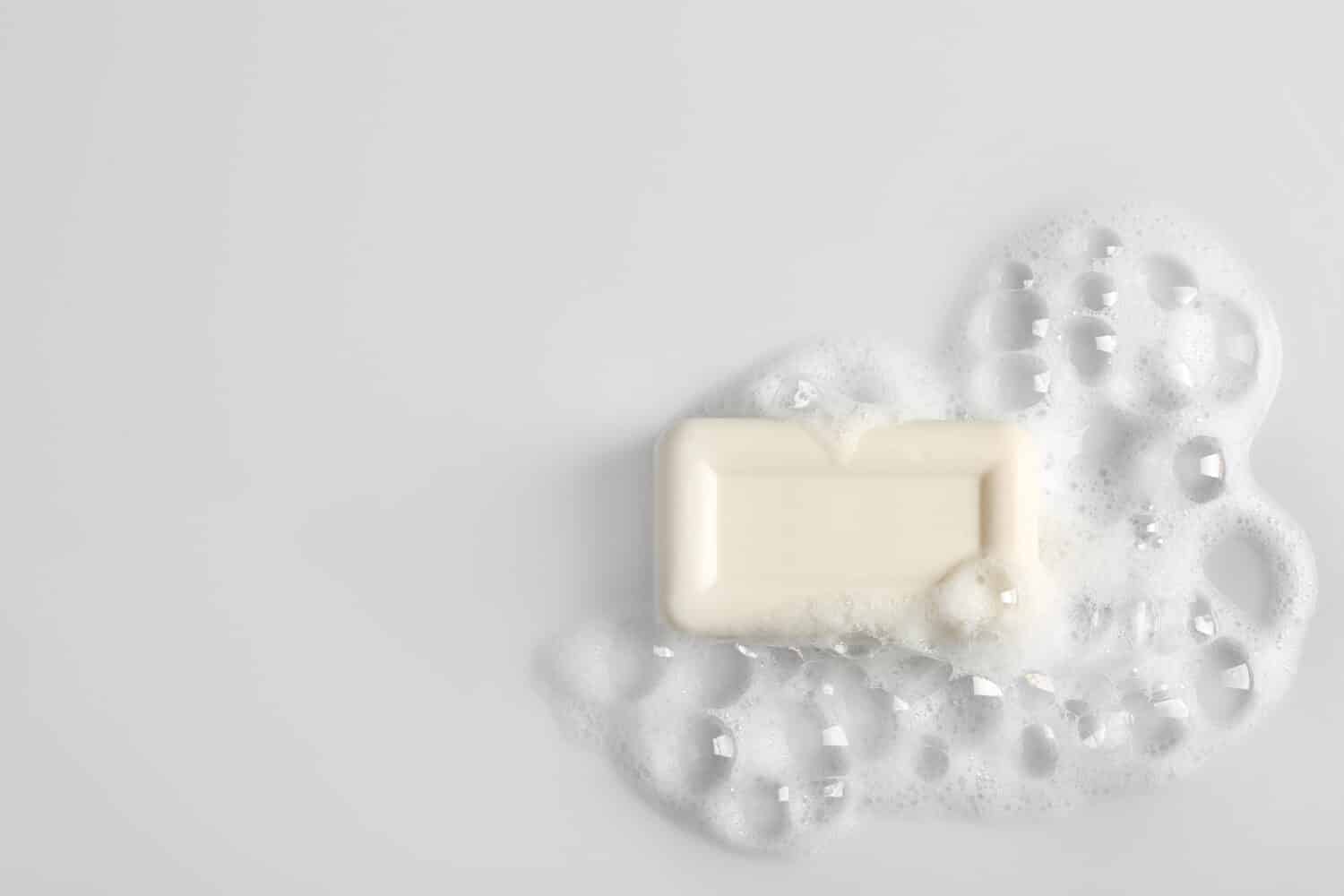 Saponetta e schiuma su sfondo bianco, vista dall'alto. Mockup per il design