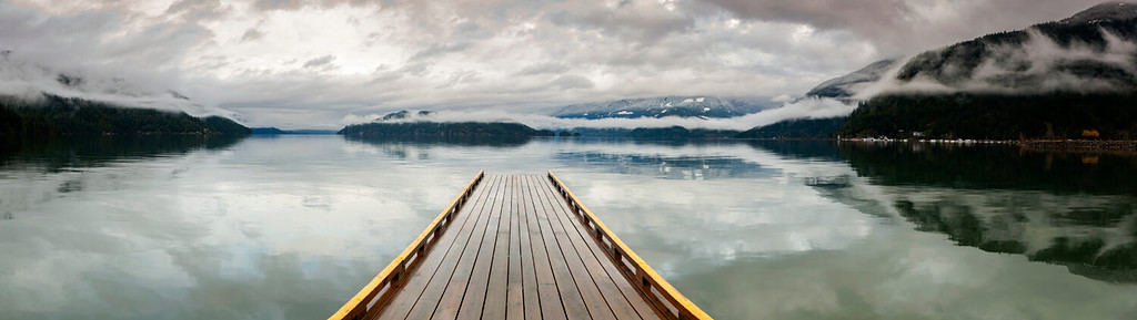 Dock in legno sul lago Harrison, British Columbia, Canada. Sembra che un molo si stia dirigendo verso il nulla su un lago nel Pacifico nordoccidentale. Resort delle sorgenti termali di Harrison.