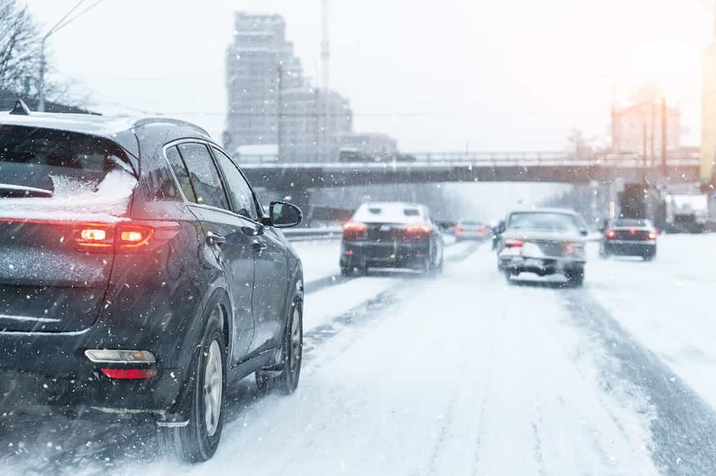 Vista panoramica innevata autostrada città strada sdrucciolevole auto in movimento movimento veloce velocità.  Nevicate pericolo blizzard cattive condizioni meteorologiche invernali.  Fondo urbano della città di snowstrom di giorno nevoso freddo