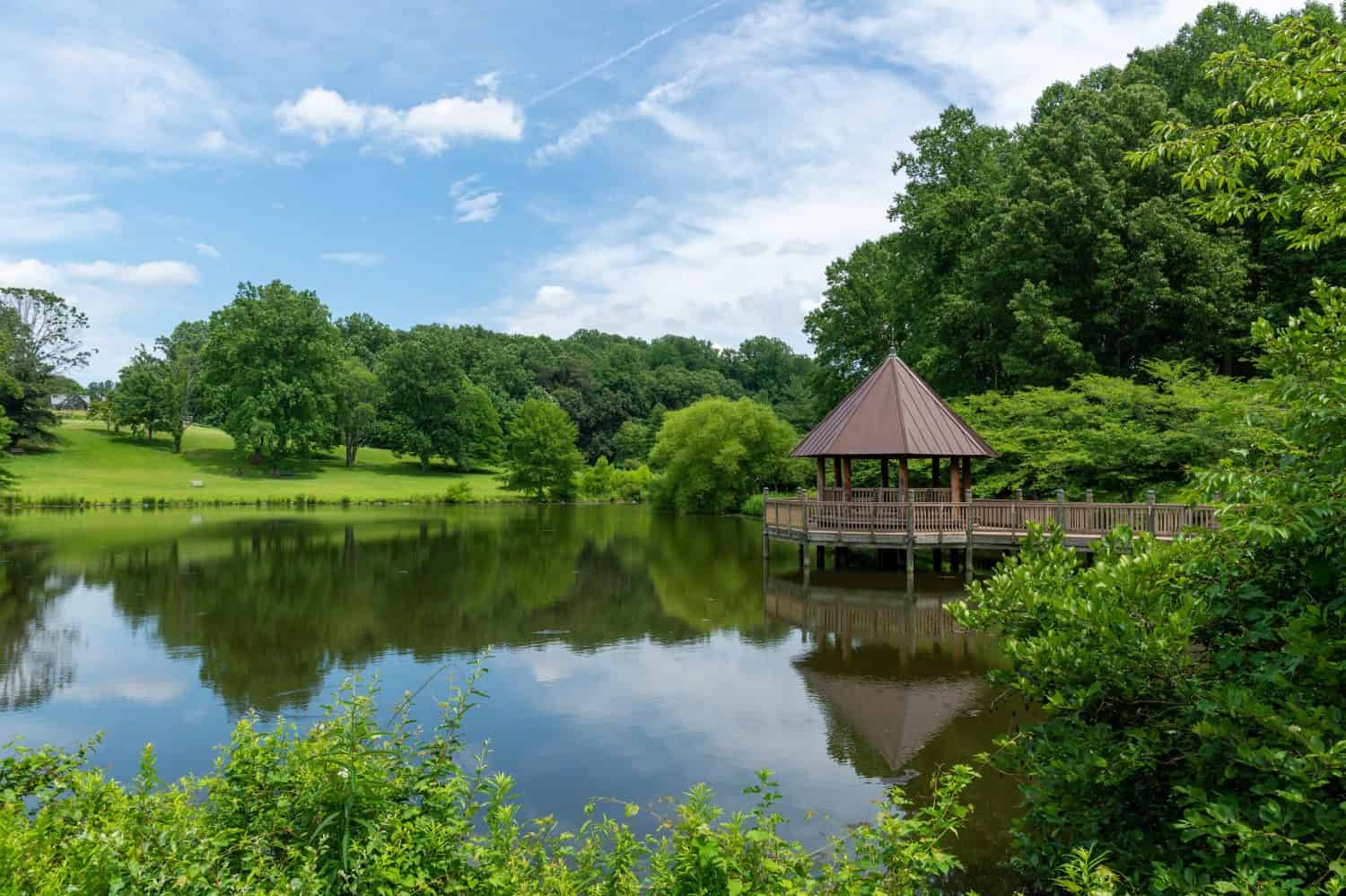 Un gazebo riflesso in uno stagno il giorno d'estate nei giardini botanici di Meadowlark a Vienna, Virginia.