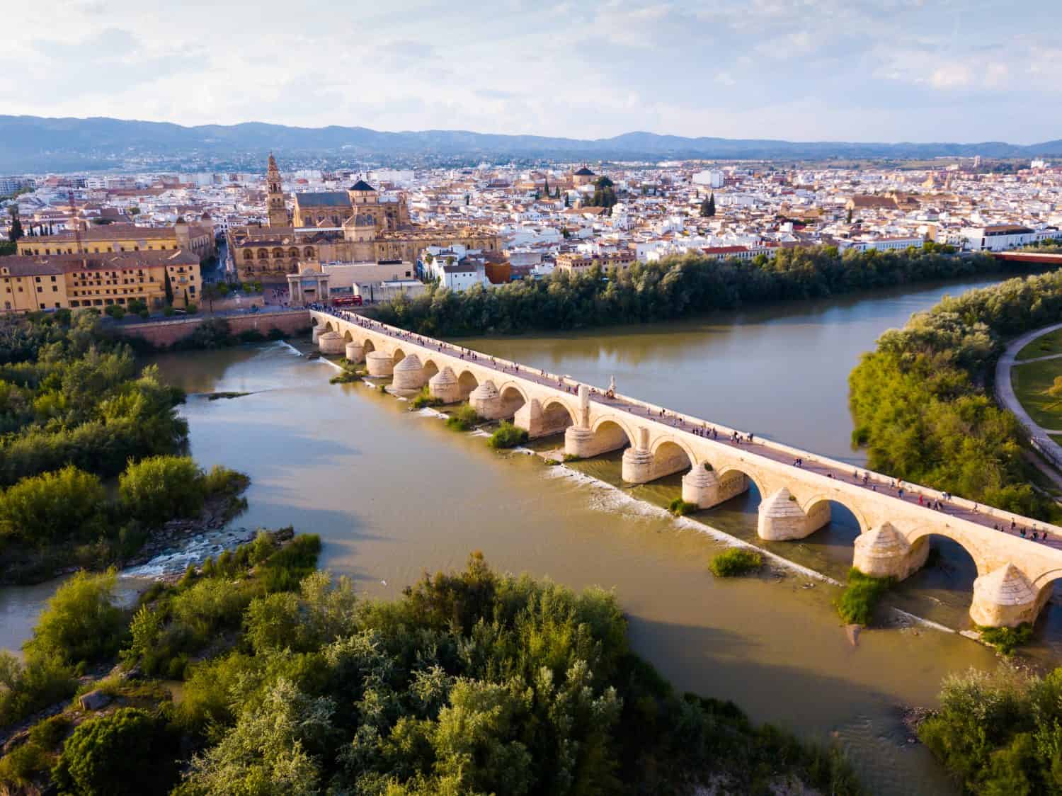 Vista aerea panoramica dell'antico ponte romano sul fiume Guadalquivir e dell'architettura moresca della Mezquita-Catedral sullo sfondo con il paesaggio urbano di Cordoba, Spagna