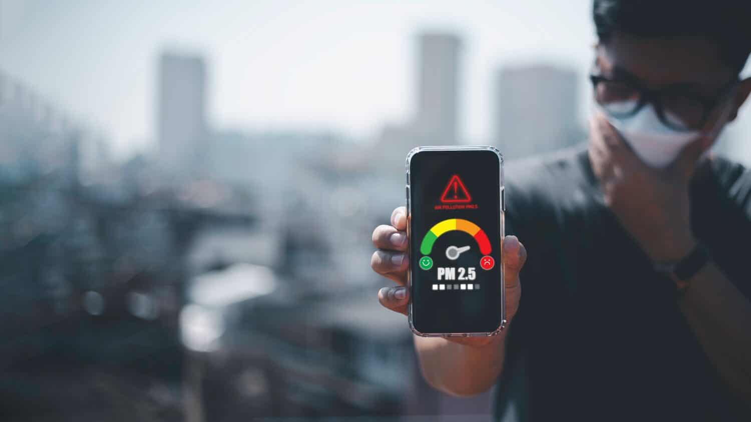 uomo che scansiona il meteo sul suo cellulare Concetto ecologico. Allergie. Mal di testa.N95 PM 2.5 da inquinamento atmosferico e polvere oltre gli standard di sicurezza. sanità, ambiente,