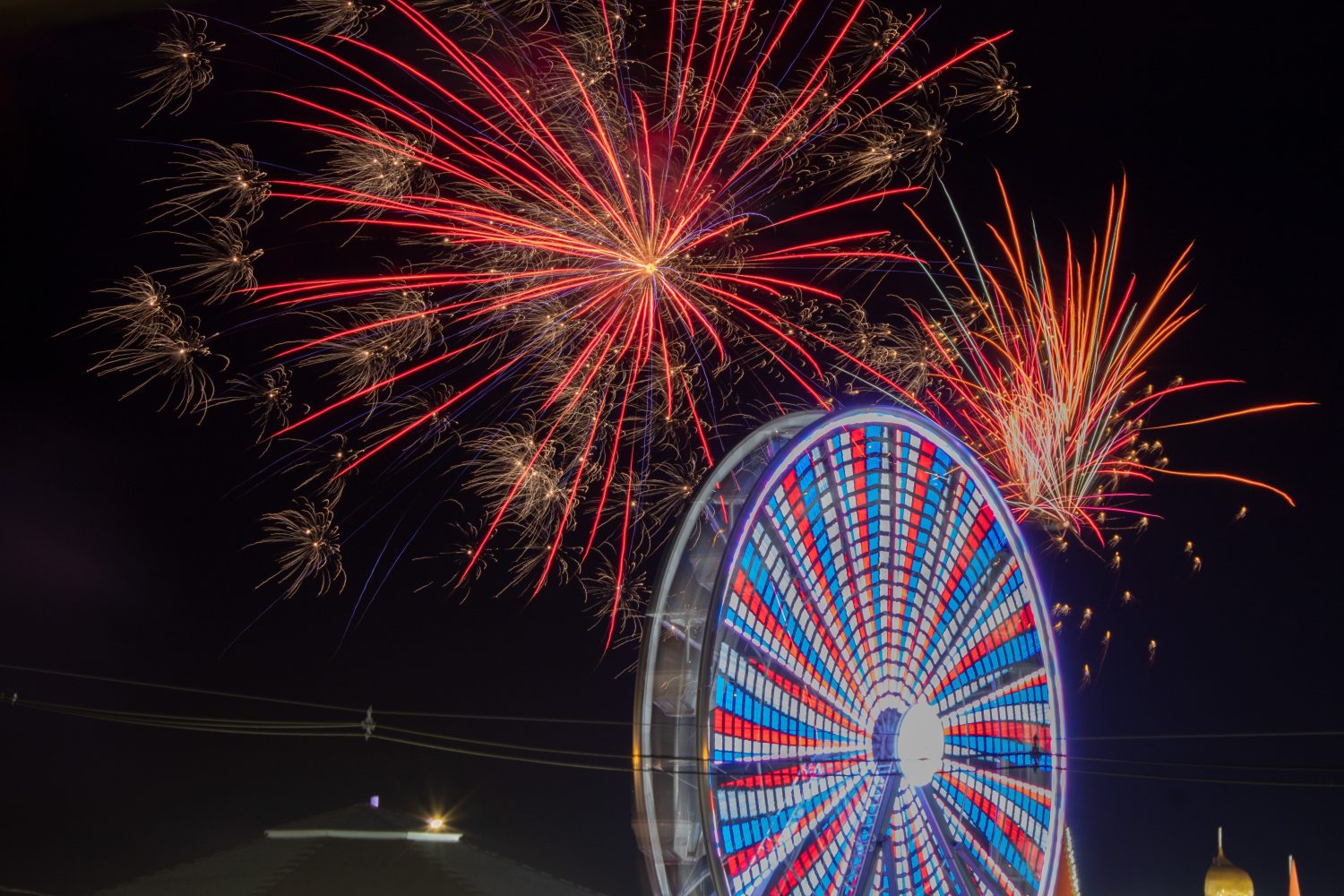 Old Orchard Beach, Maine - Fuochi d'artificio scattati con una lunga esposizione durante lo spettacolo pirotecnico settimanale, con la ruota panoramica del parco divertimenti in primo piano
